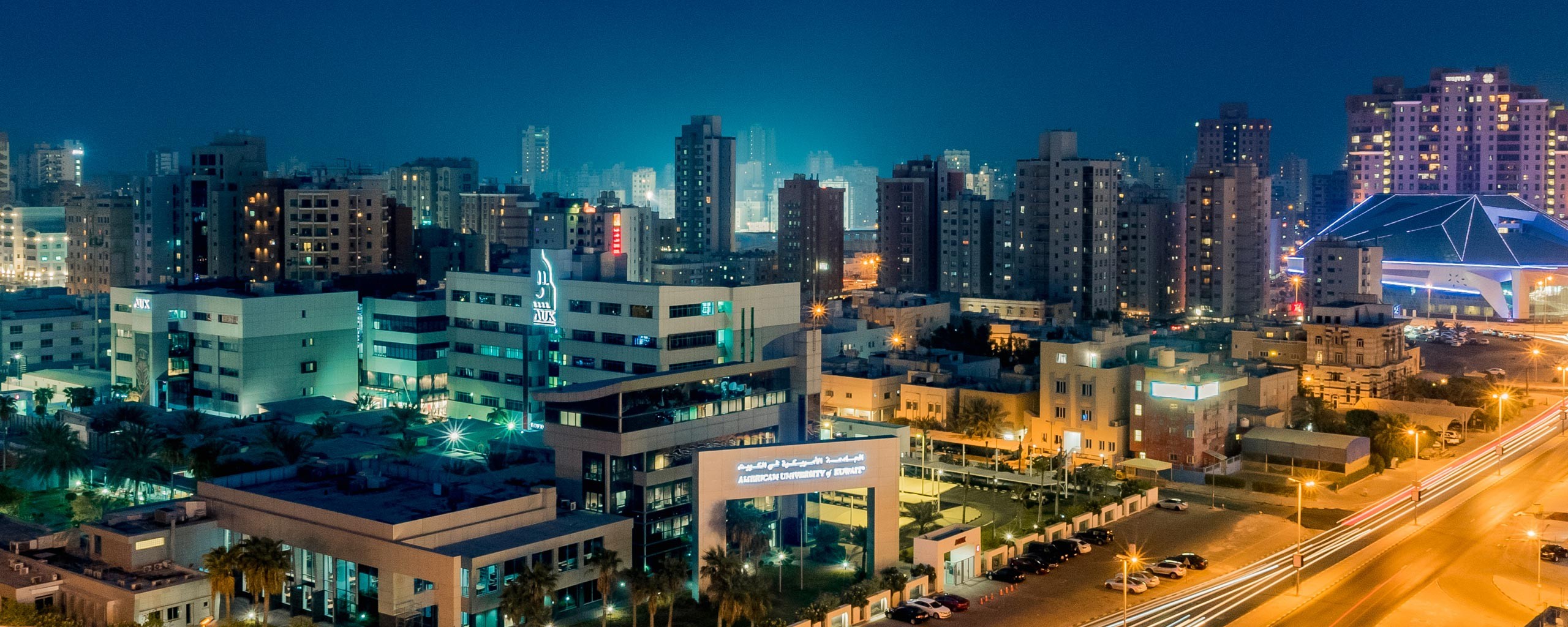A night view of the American University of Kuwait and Kuwait City in the background.