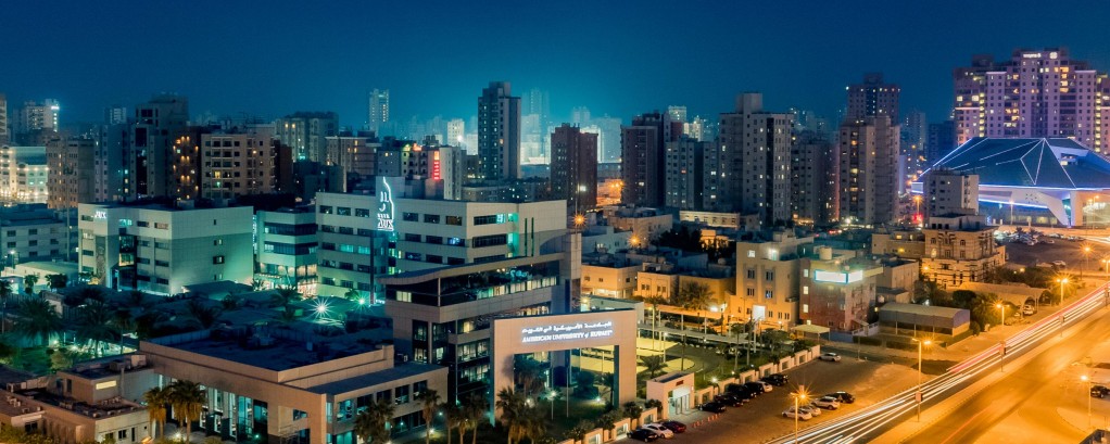 A night view of the American University of Kuwait and Kuwait City in the background.